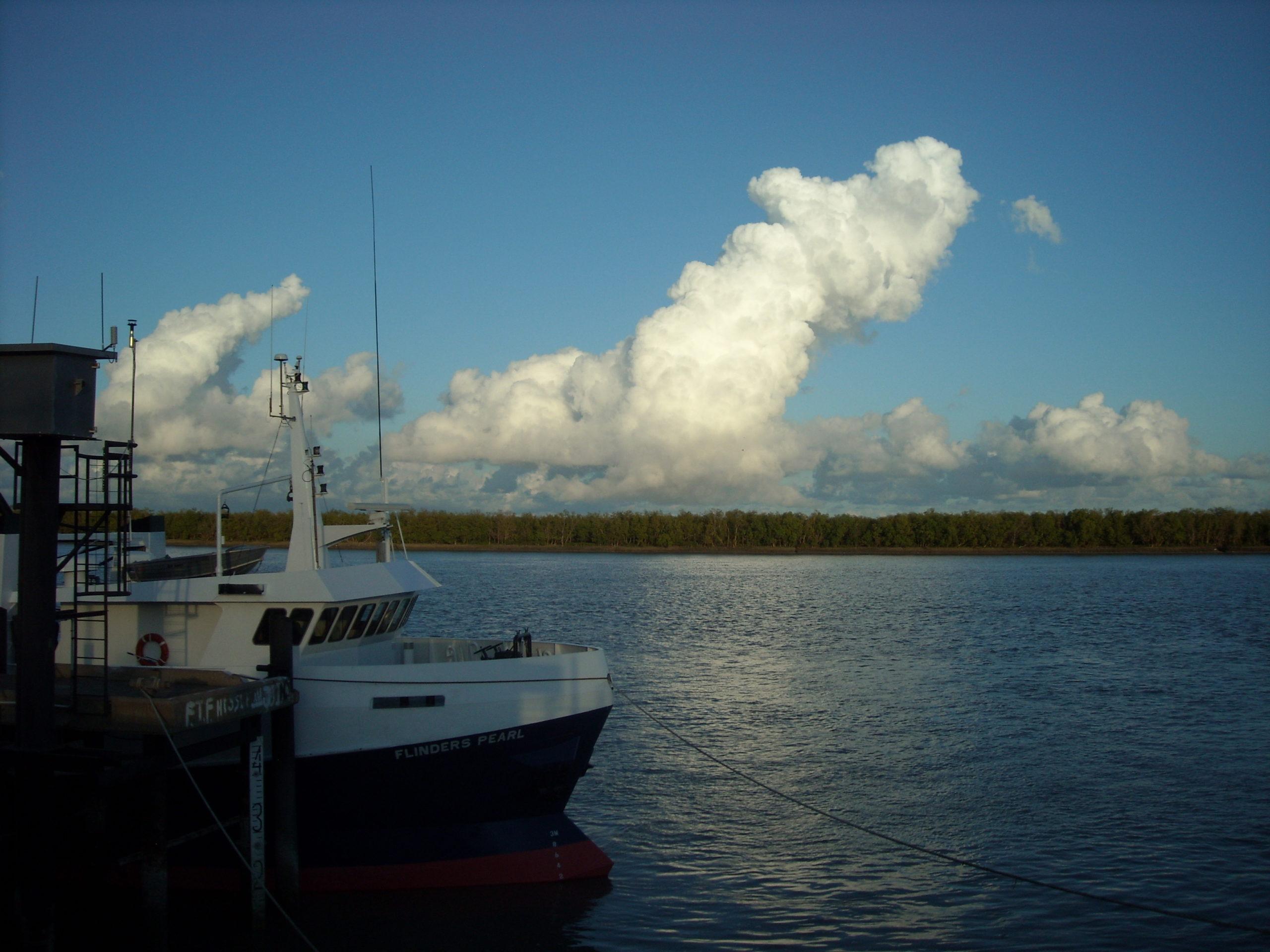 Prawn trawler moored at a jetty in Karumba with a billowing wet season clowd in the background.