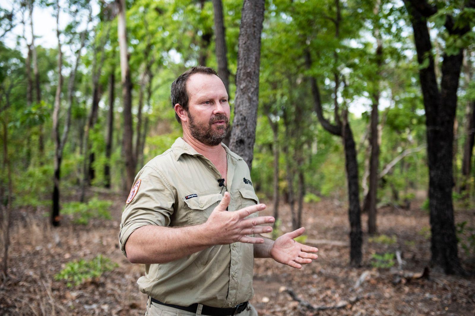 Steve Dwyer in his khaki uniform of an NT park ranger in front of a vibrant green savanna backgrown